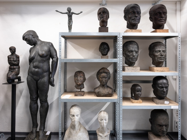 Skulpturensammlung aus Bronze und Gips im Beeskower Depot. Zu sehen sind Ganzk&ouml;rperakte, Portr&auml;tb&uuml;sten und Fragmente in diversen Posen und Stilen, arrangiert auf Metallregalen in einem Lagerraum.