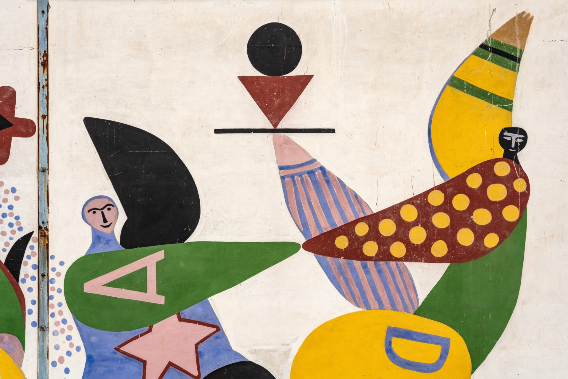 Ausschnitt eines Wandgem&auml;ldes von Erika St&uuml;rmer-Alex im abstrakten Stil, das geometrische Formen und stilisierte Figuren zeigt. Das Bild enth&auml;lt verschiedene Elemente wie einen schwarzen Kreis &uuml;ber einem roten Dreieck, eine Figur in Blau mit einem gr&uuml;nen Element und dem Buchstaben 'A', sowie eine vogelartige Form mit gelben Punkten auf braunem Grund und blau-wei&szlig;en Streifen. Die Komposition ist in kr&auml;ftigen Farben (Gr&uuml;n, Gelb, Blau, Rot, Schwarz) auf wei&szlig;em Hintergrund gehalten und erinnert an den Stil der klassischen Moderne.