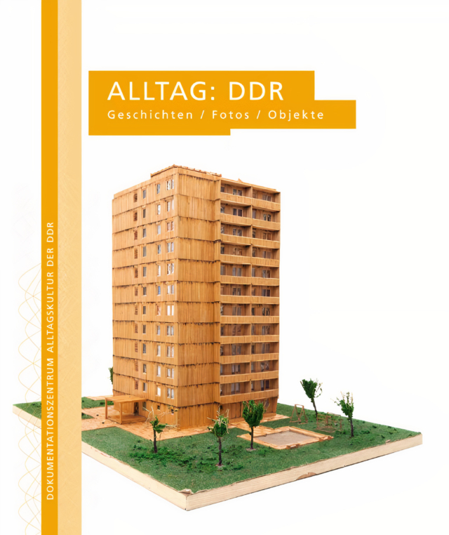 Unter dem auf gelben Untergrund hervorgehobenen Titel 'Alltagskultur: DDR' präsentiert sich ein detailliertes Architekturmodell aus hellem Holz: Ein elfgeschossiger Plattenbau mit charakteristischer Rasterfassade und Balkonen steht auf einer begrünten Grundplatte mit kleinen Bäumen. Ein orangefarbener vertikaler Streifen am linken Bildrand kennzeichnet die Publikation als Teil der Reihe 'Dokumentationszentrum Alltagskultur der DDR'.